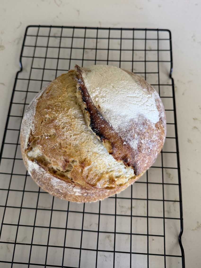 Loaf of sourdough bread sitting on a wire rack.